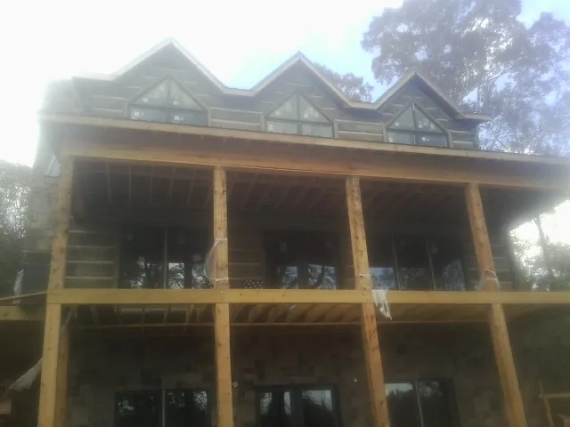 Dormers and porch framing on a large log home under construction — Roof Coating work by our crew in Ecorse