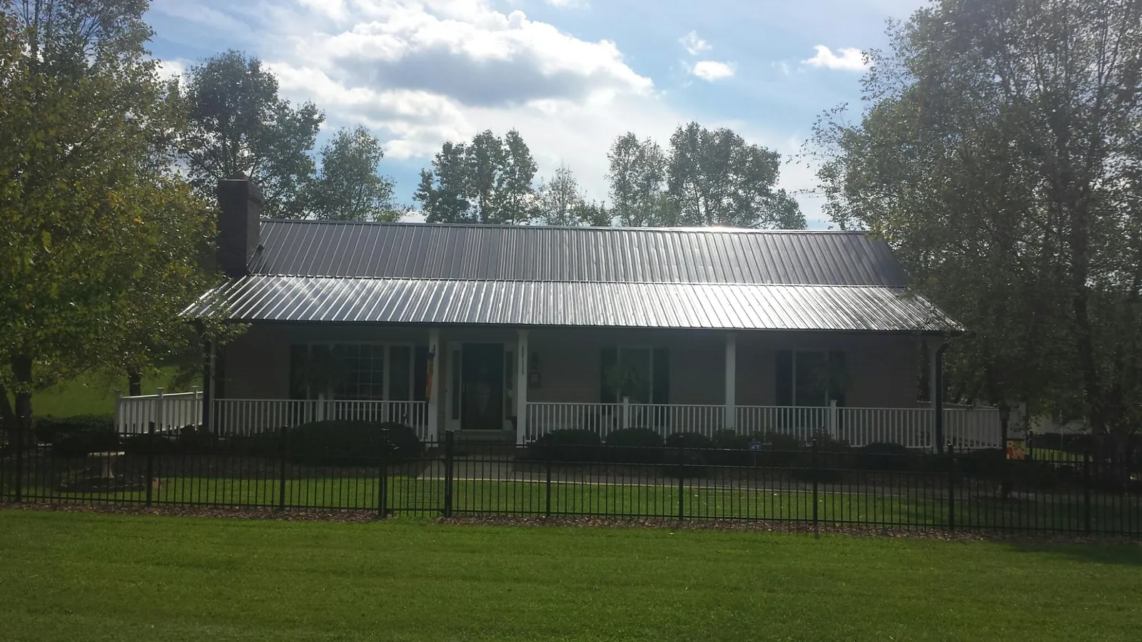 Gray metal roof on a brick ranch with a full width front porch — Gutter Guard Installation work by our crew in Ecorse