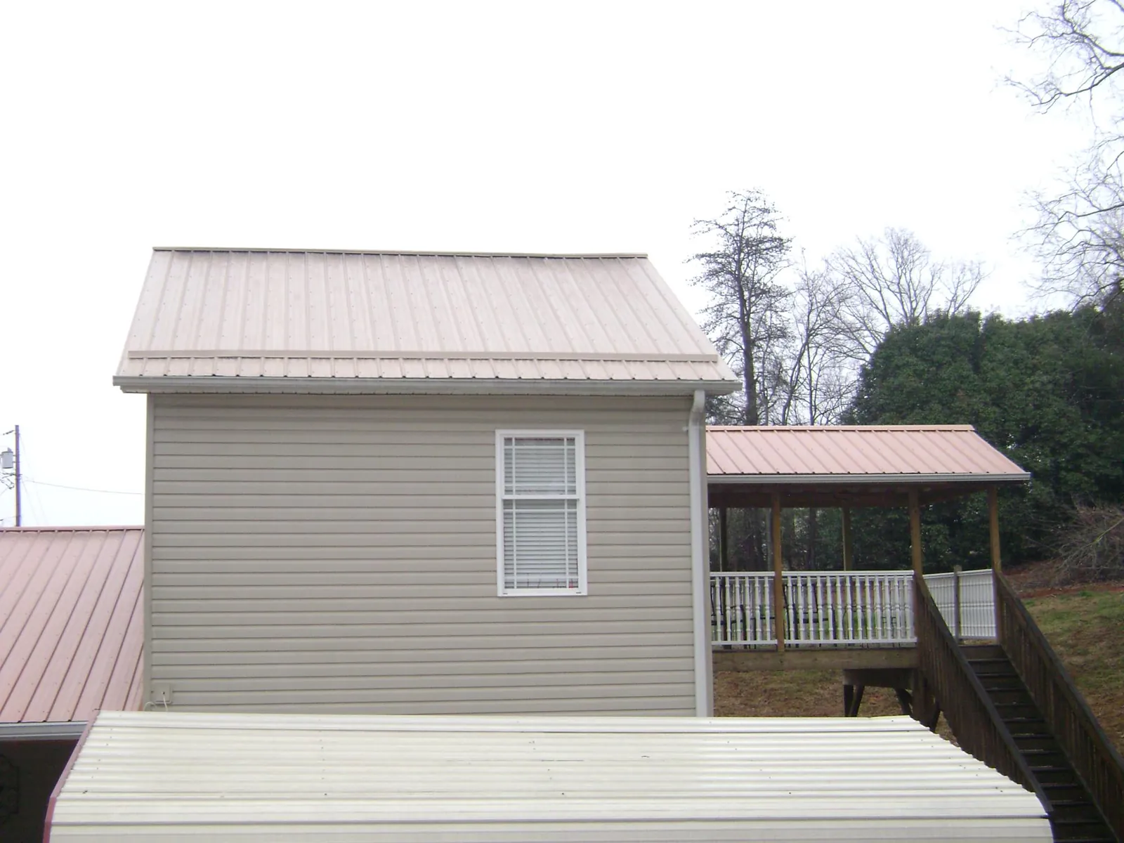 Tan metal roofs on a two story addition and attached porch, from a Roof Replacement job in Ecorse