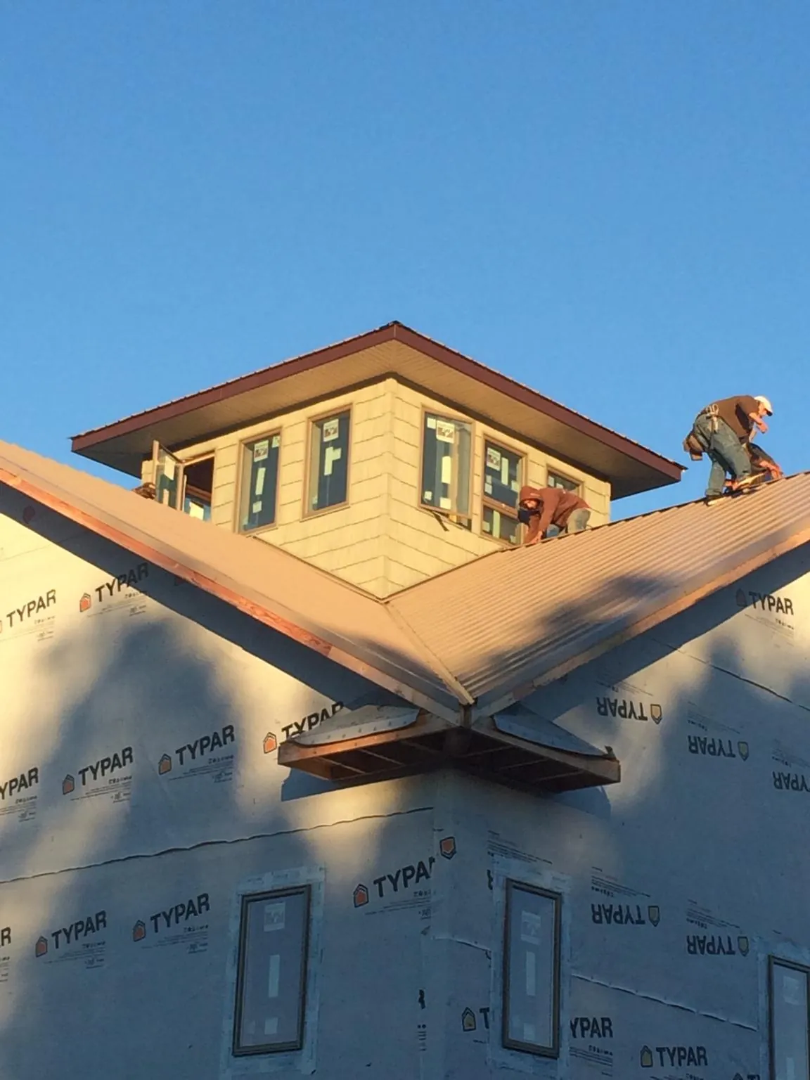 Roofers working around a rooftop cupola on a new metal roof at sunset — Roof Waterproofing in Ecorse by Roofing Brothers